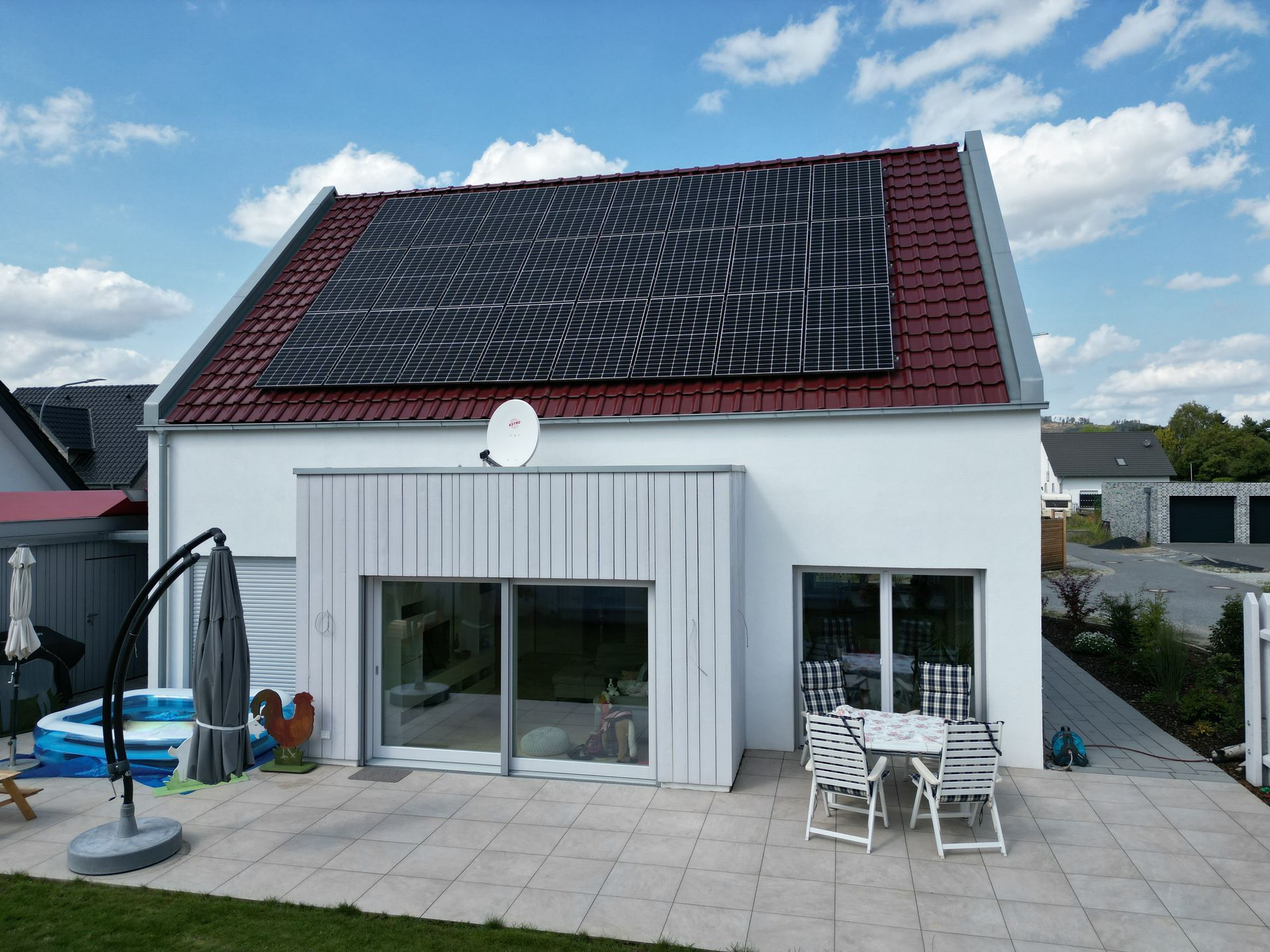Neubauhaus mit einem Holzanbau. Auf dem Dach Photovoltaik