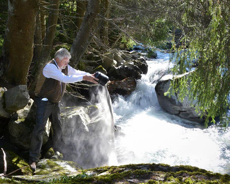 Ein Mann streut Asche in einen Bach