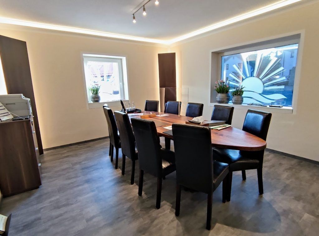 Ein ovaler Tisch mit 10 Stühlen, an dem Besprechungen stattfinden