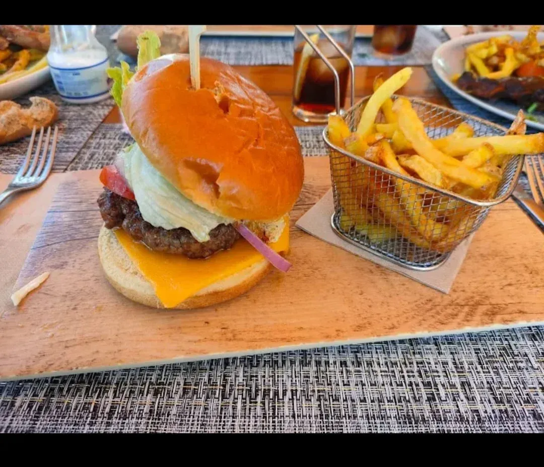 Una hamburguesa con queso y diversos acompañamientos