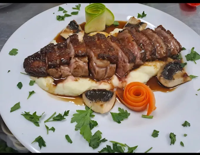 Una pechuga de pato en rodajas sobre puré de patatas