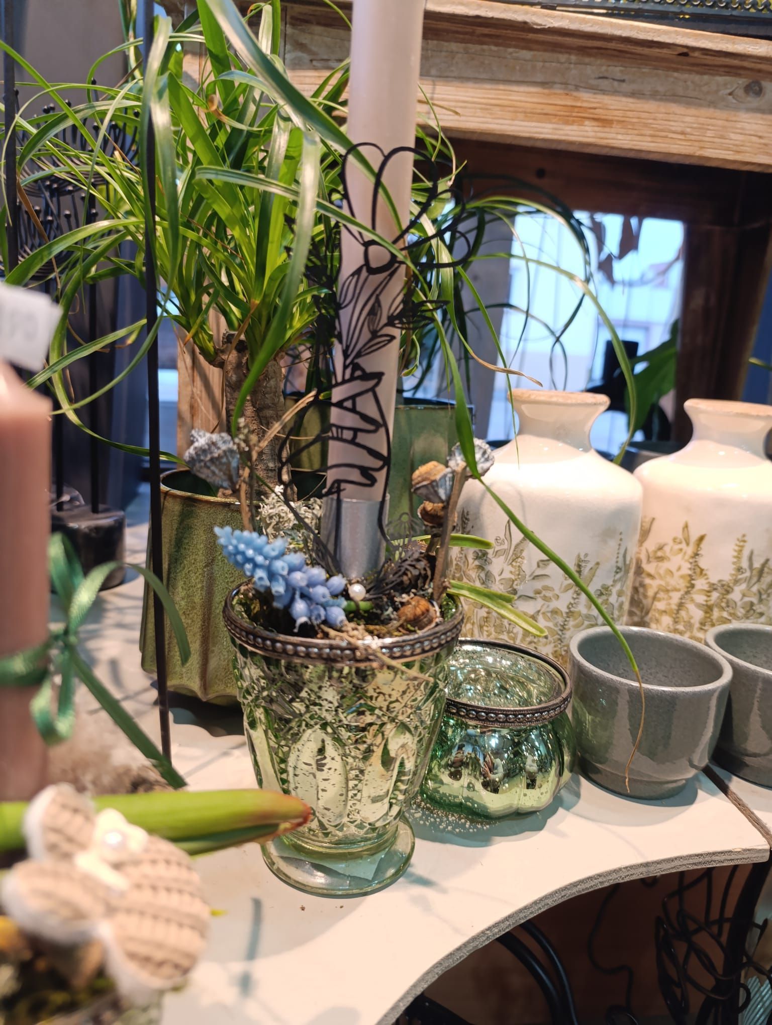 Ein Tisch mit vielen Topfpflanzen und Kerzen darauf.