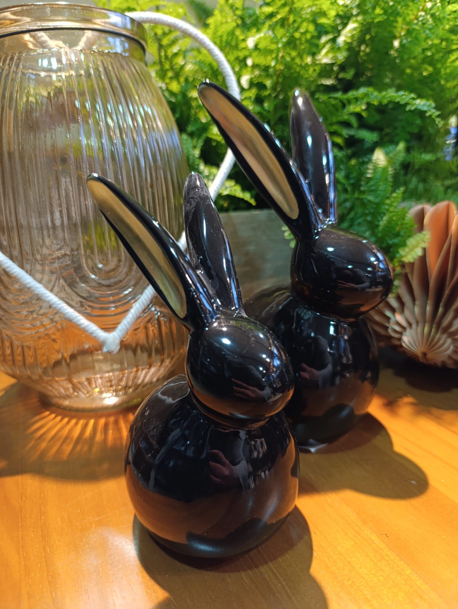 Zwei schwarze Keramikhasen sitzen auf einem Holztisch.
