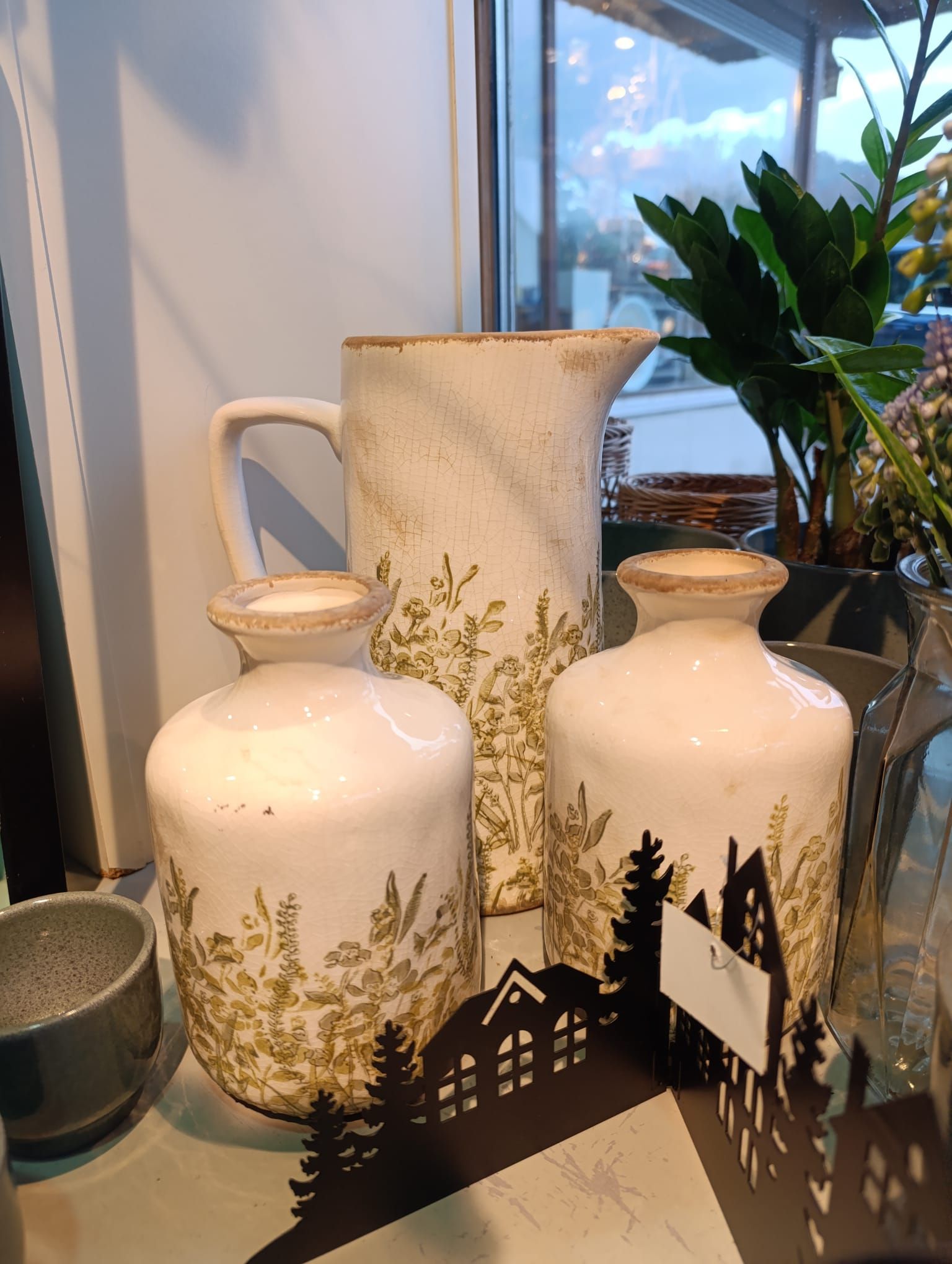 Drei Vasen stehen auf einem Tisch vor einem Fenster.