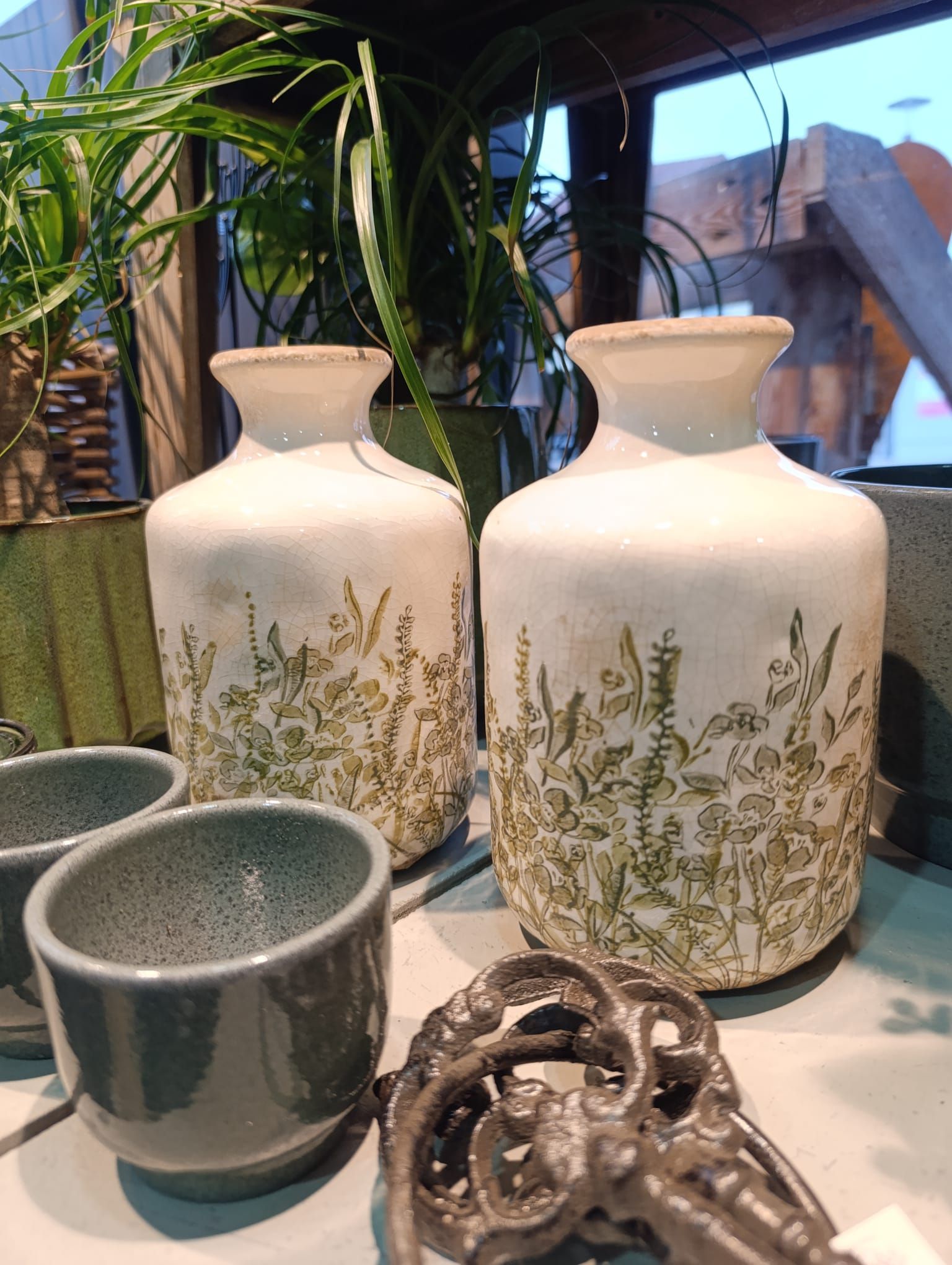 Ein paar Vasen stehen neben einer Pflanze auf einem Tisch.