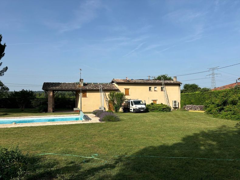 Un jardin avec une piscine, une pelouse et une petite maison jaune.