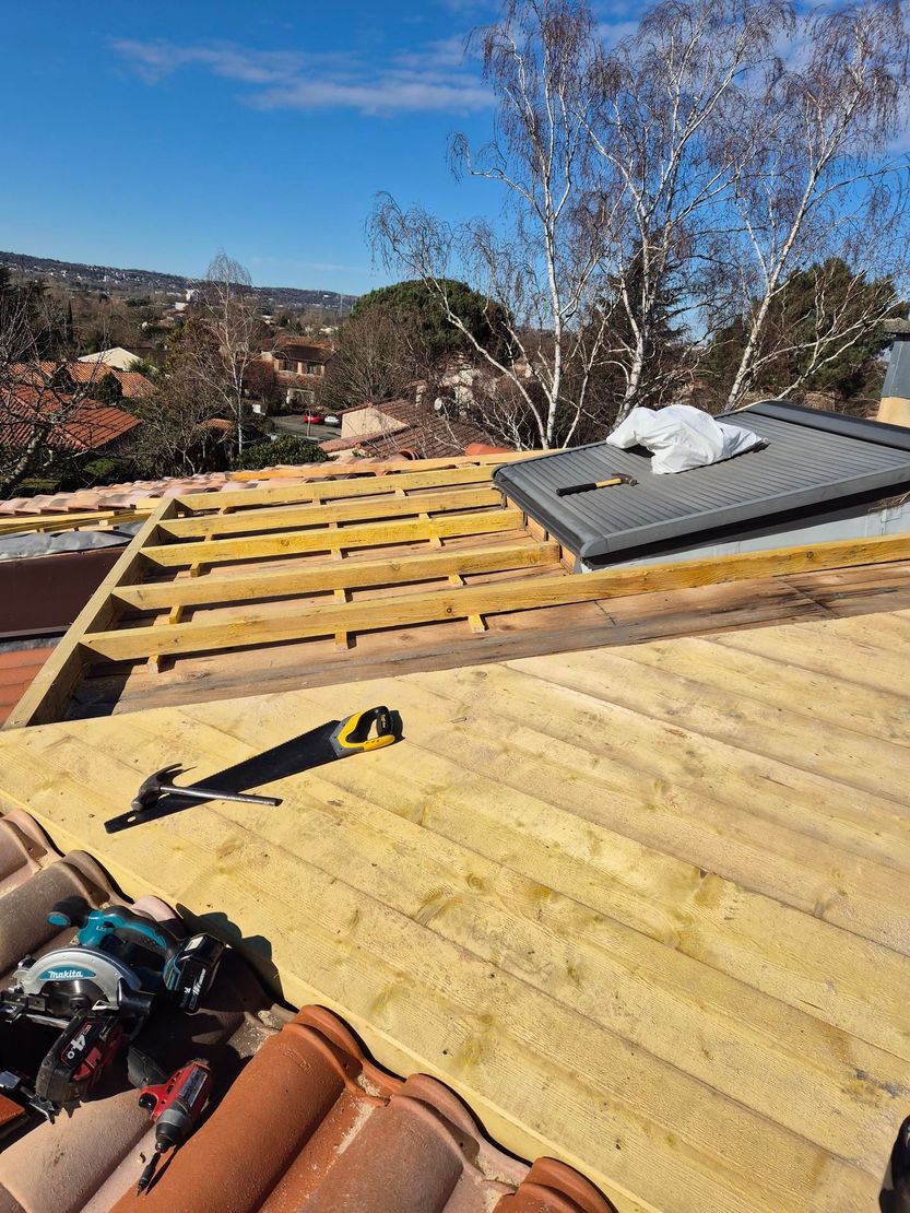 Charpente en construction avec outils et puits de lumière gris.