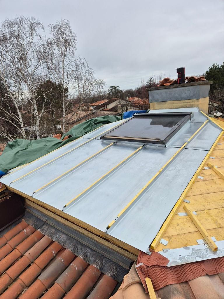 Toit avec panneaux solaires installés à côté d'une fenêtre de toit, vue depuis le toit en pente d'une maison.
