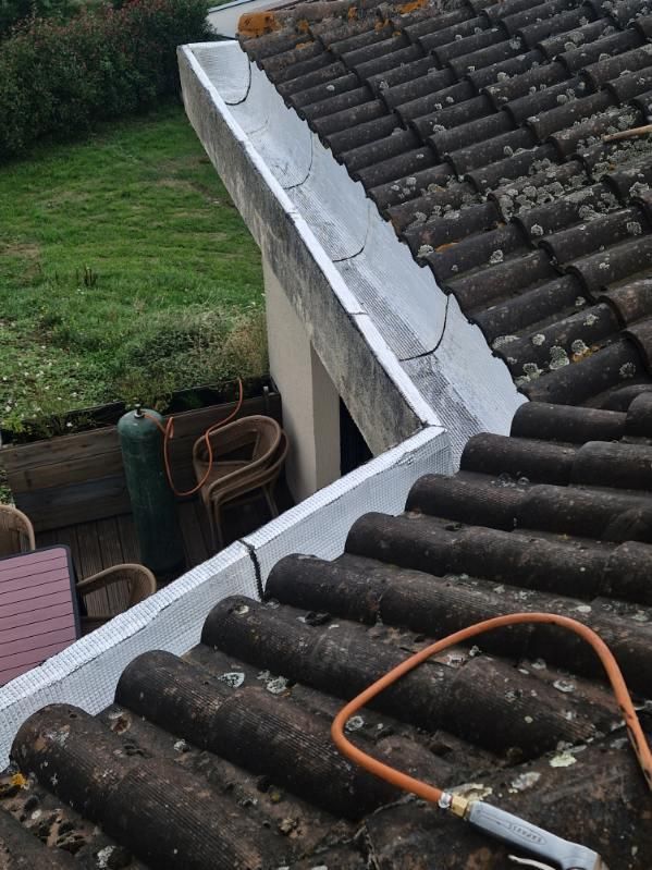 Gouttière et angle de toiture en tuiles avec bandeau blanc, vus de dessus.