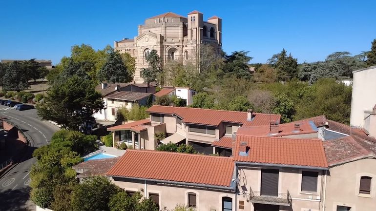 Des échafaudages recouvrent un bâtiment en briques lors de travaux de rénovation extérieure dans une rue.