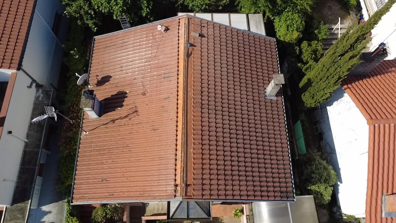Vue aérienne d'un toit de tuiles rouges entre des maisons voisines et des arbres