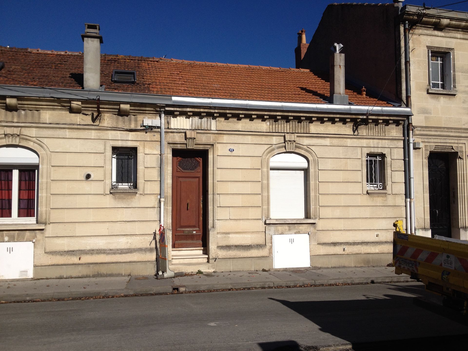 Une maison avant une surélévation avec des volets blancs