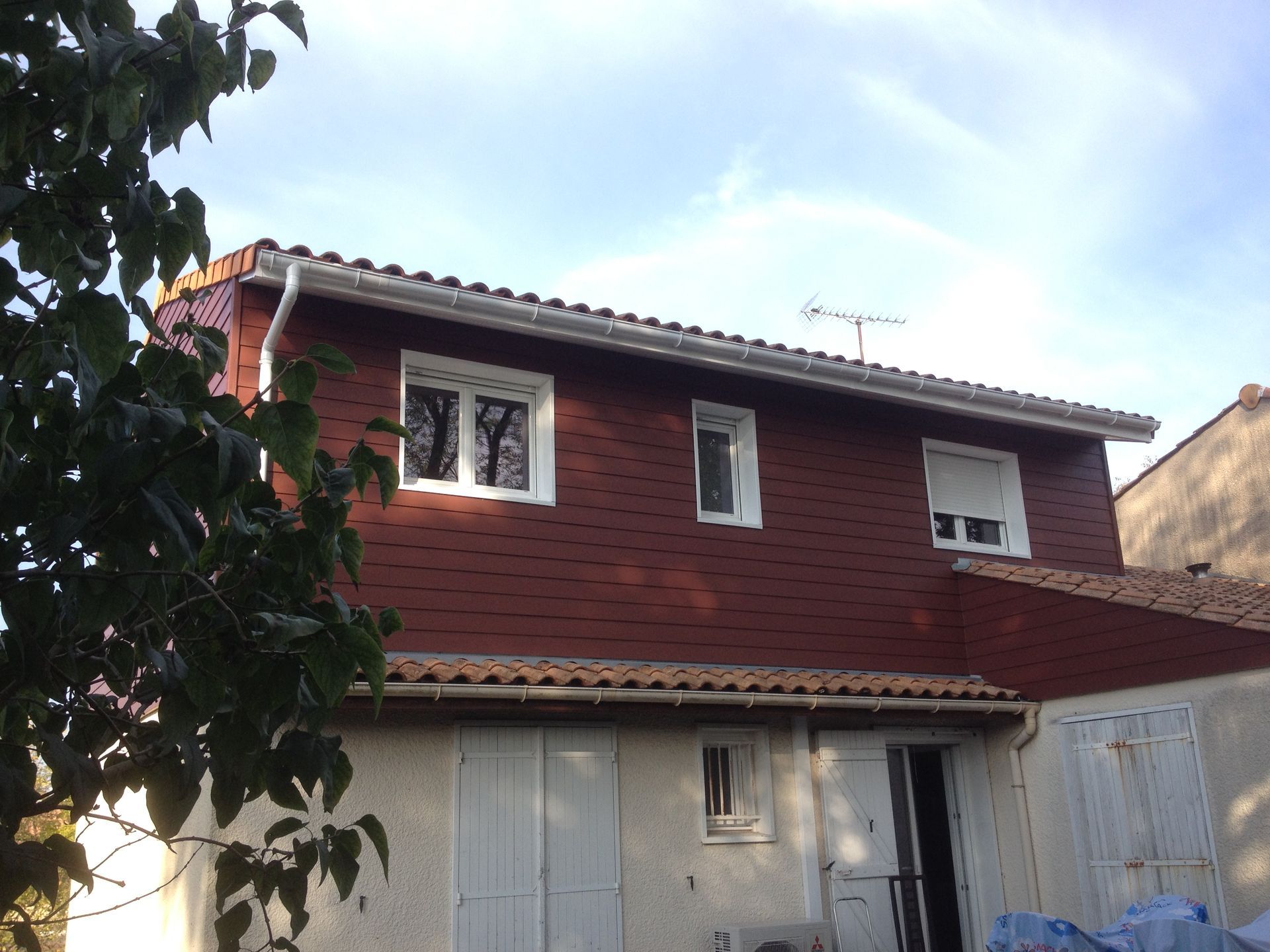 Une maison avec une surélévation en bois rouge