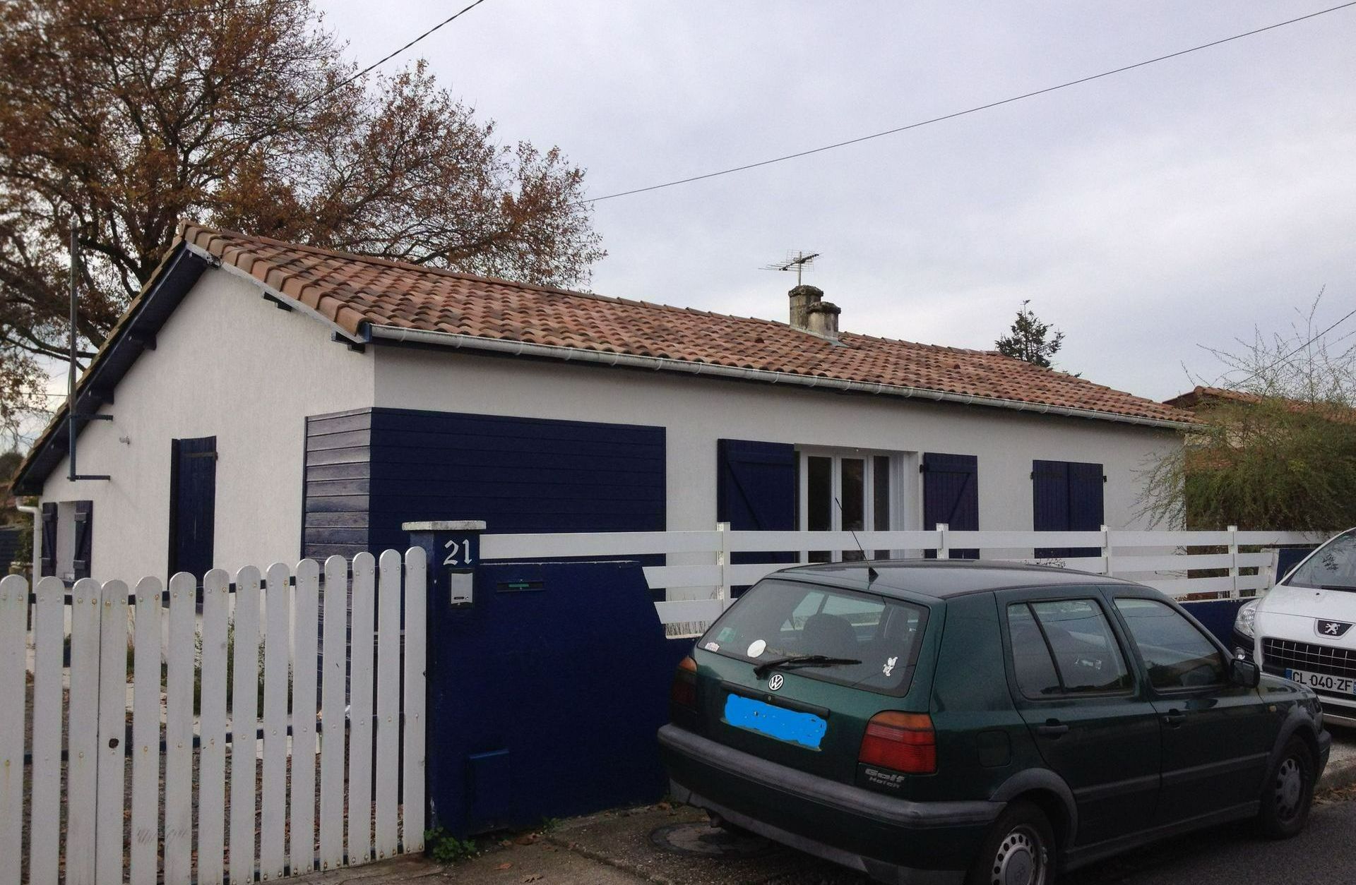 Une maison avec une voiture verte devant