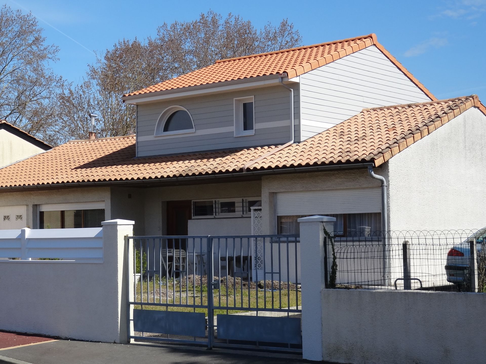 Une maison après la surélévation avec un portail bleu