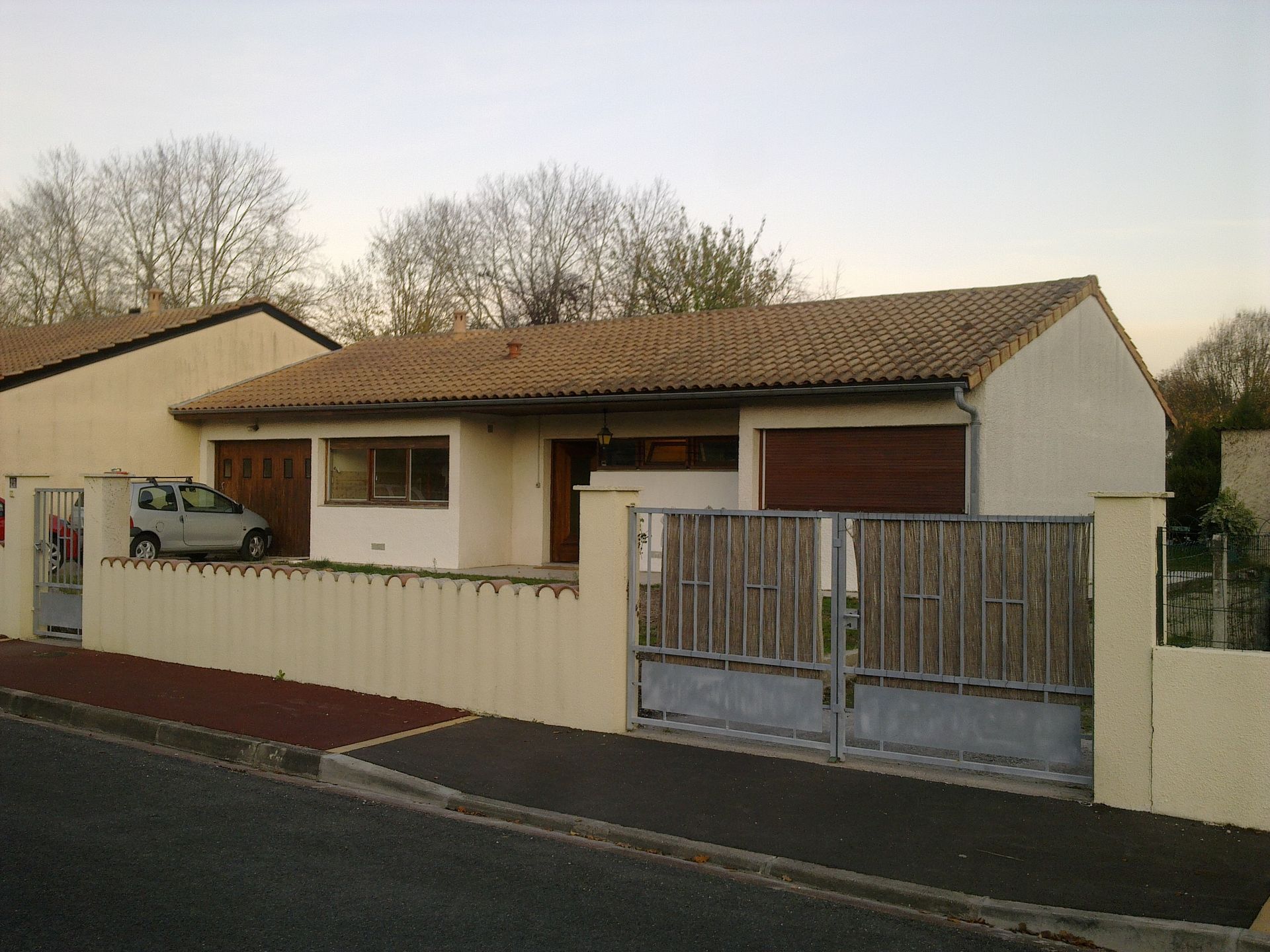 Une maison beige avec un portail bleu