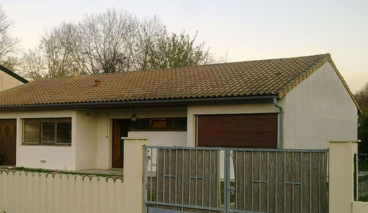 Une maison avant la surélévation avec un portail vert