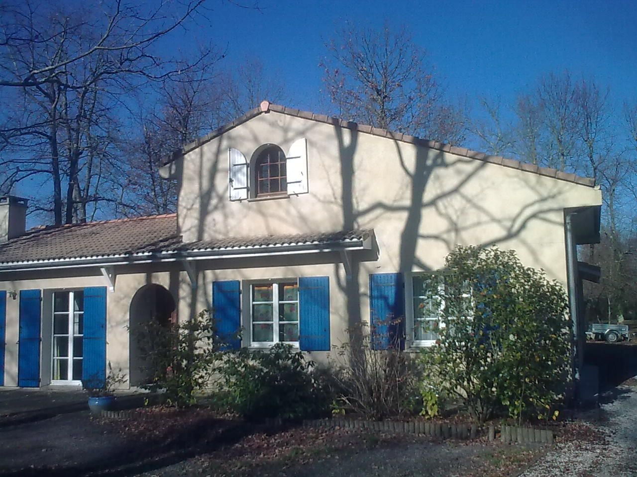 Une maison avec une surélévation avec des petits volets blancs