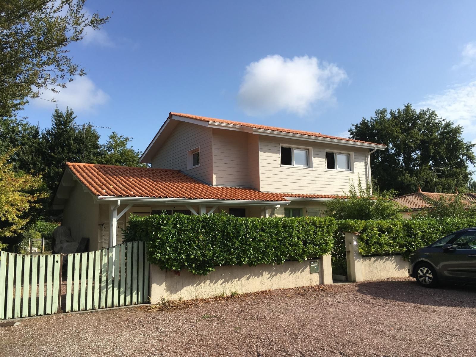 Une maison avec un portail vert et une surélévation 