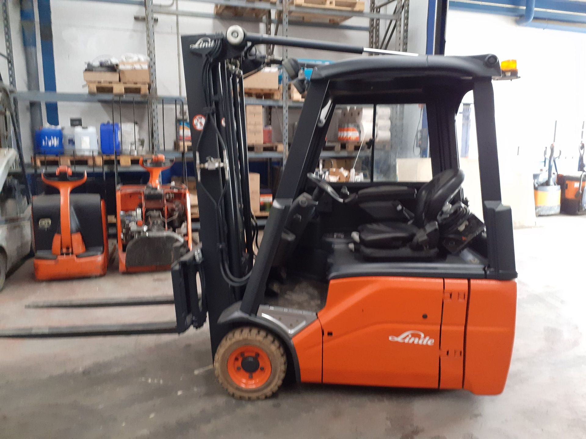 Una carretilla elevadora de color naranja y negro está estacionada en un almacén.