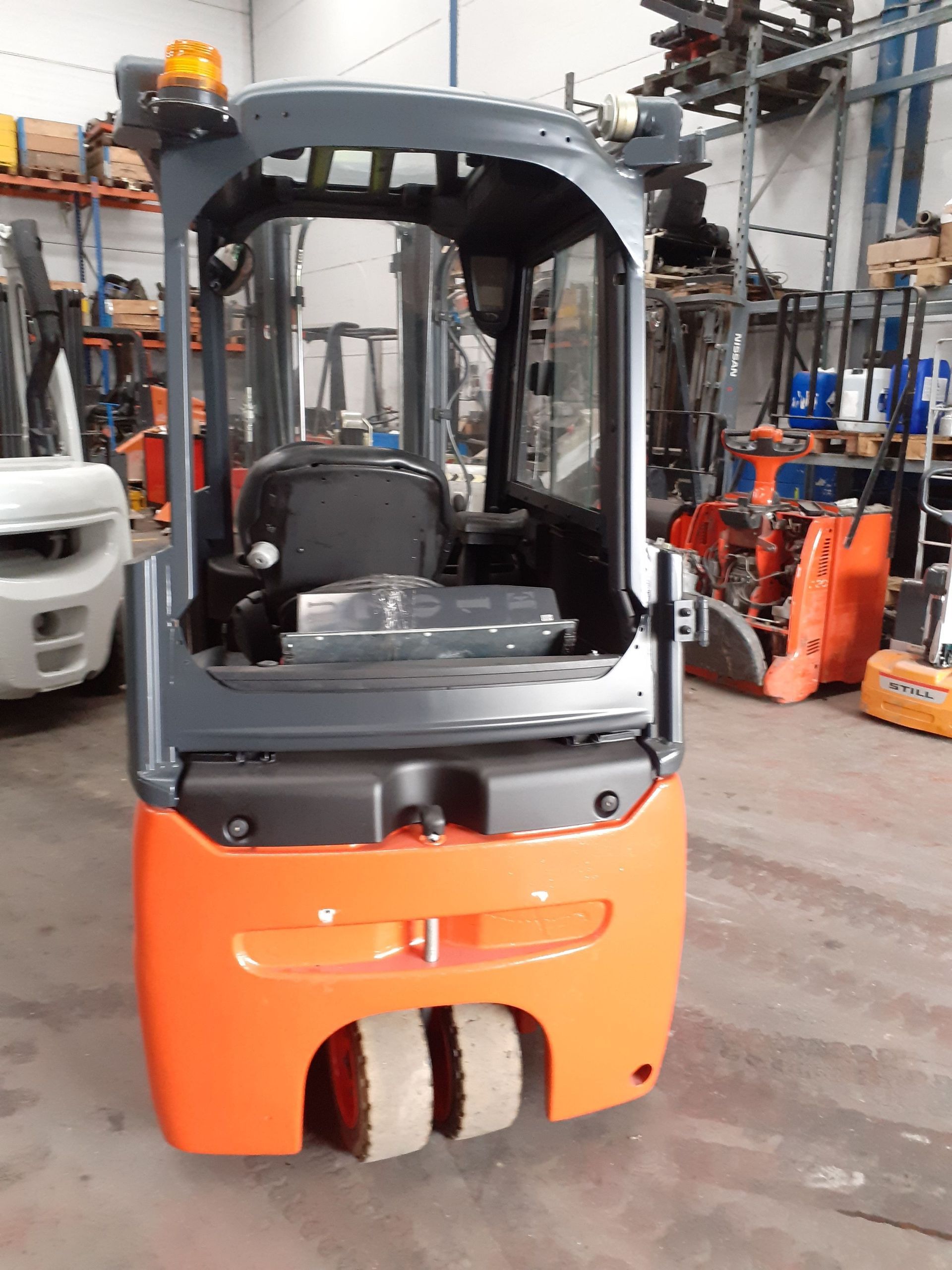 Una carretilla elevadora naranja está estacionada en un almacén.