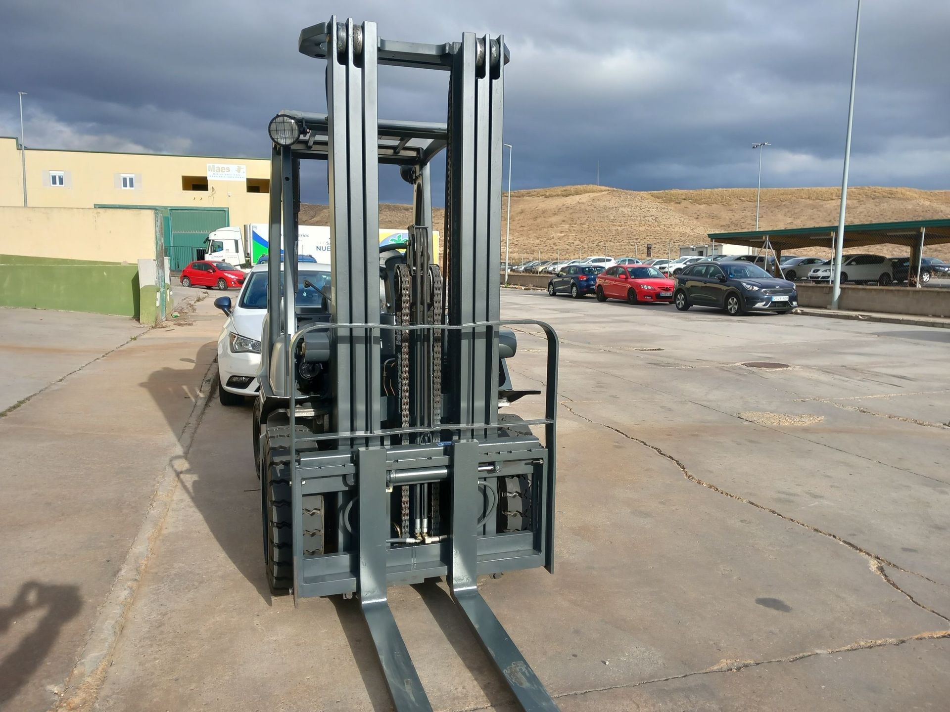 Una carretilla elevadora está estacionada en un estacionamiento frente a un edificio.