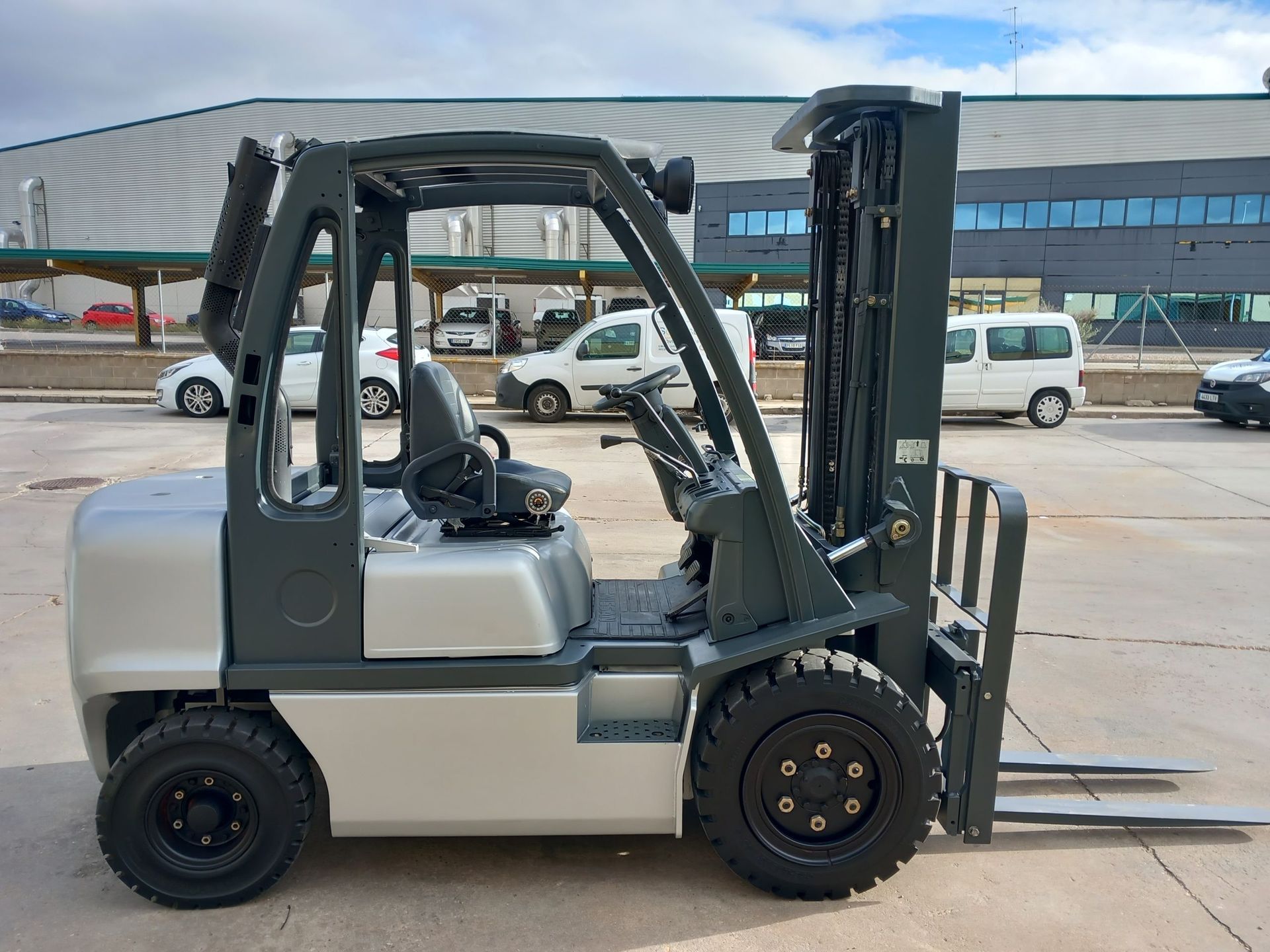 Una carretilla elevadora está estacionada en un estacionamiento frente a un edificio.