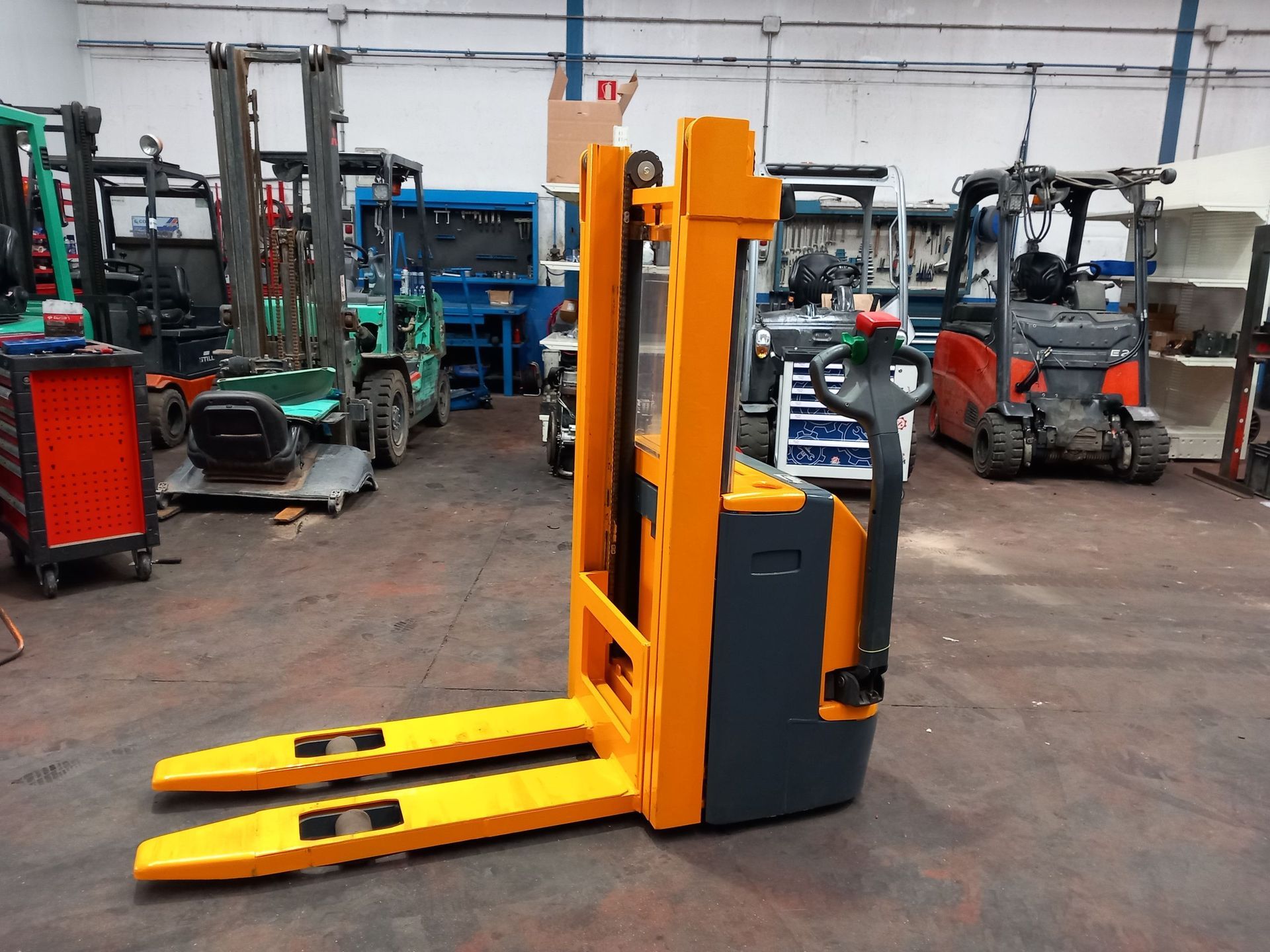 Una carretilla elevadora amarilla está en un almacén con otras carretillas elevadoras