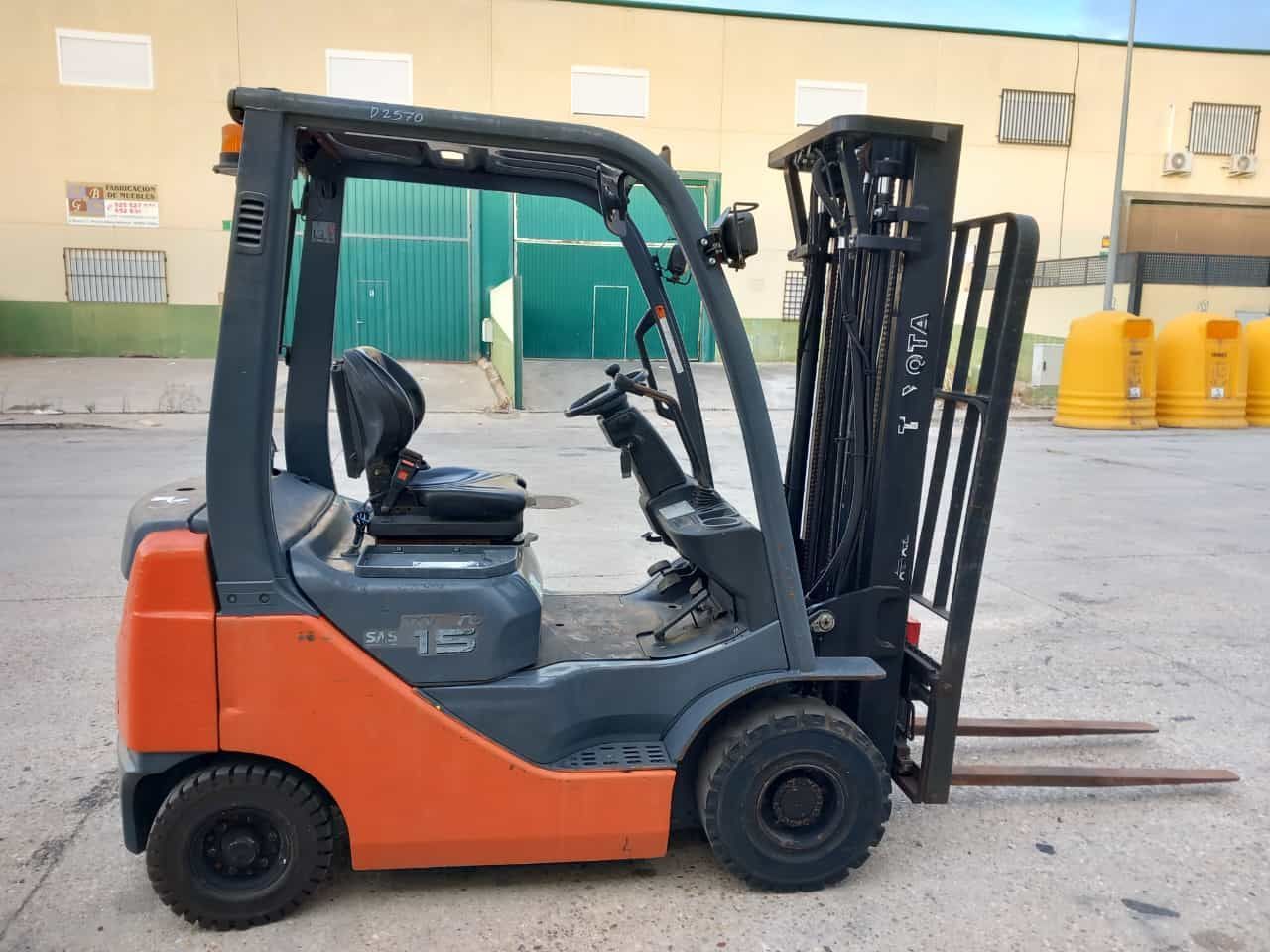 Una carretilla elevadora de color naranja y negro está estacionada frente a un edificio.