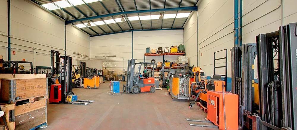 Un gran almacén lleno de muchas carretillas elevadoras.