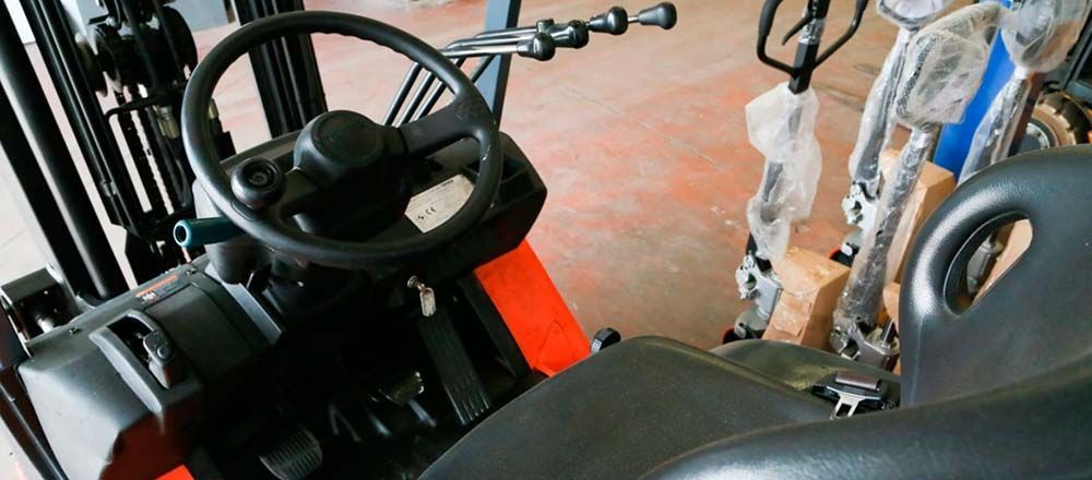 El interior de una carretilla elevadora con volante y asiento.