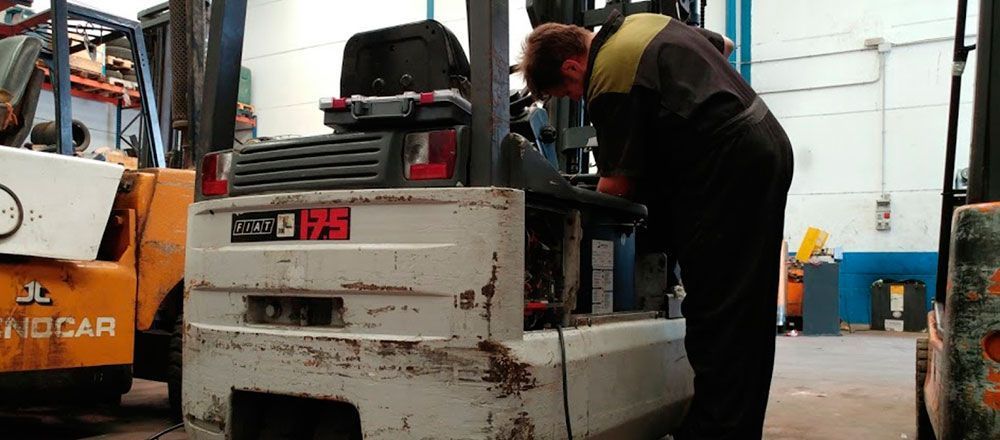 Un hombre está trabajando en una carretilla elevadora en un almacén.