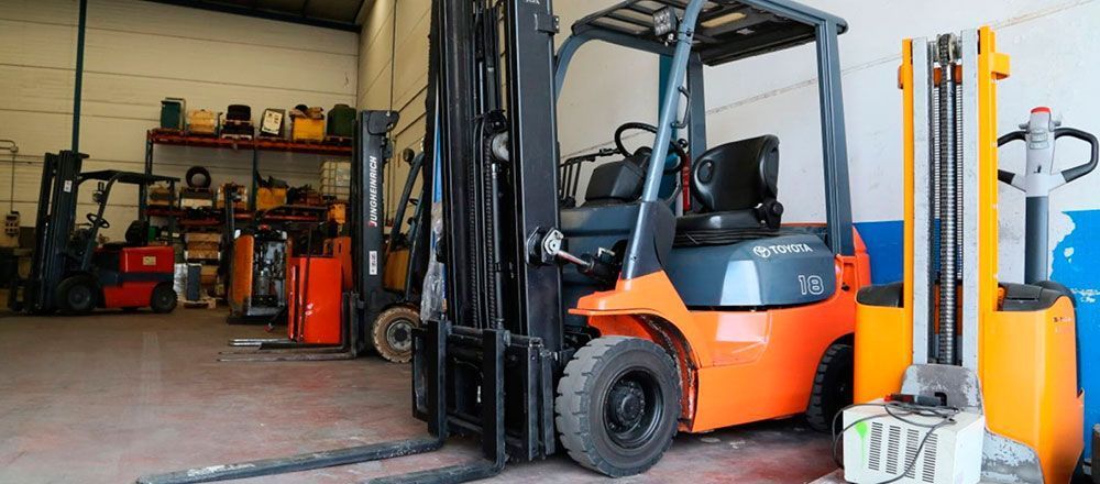 Una carretilla elevadora está estacionada en un almacén al lado de otra carretilla elevadora.