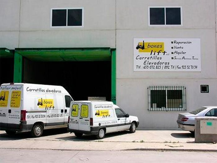 Dos furgonetas elevadoras están estacionadas frente a un edificio