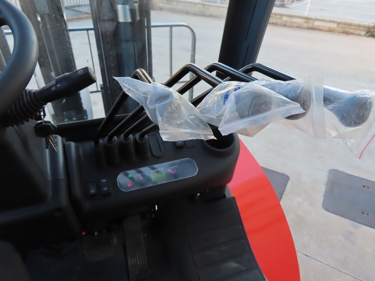 El interior de una carretilla elevadora con bolsas de plástico en los controles.