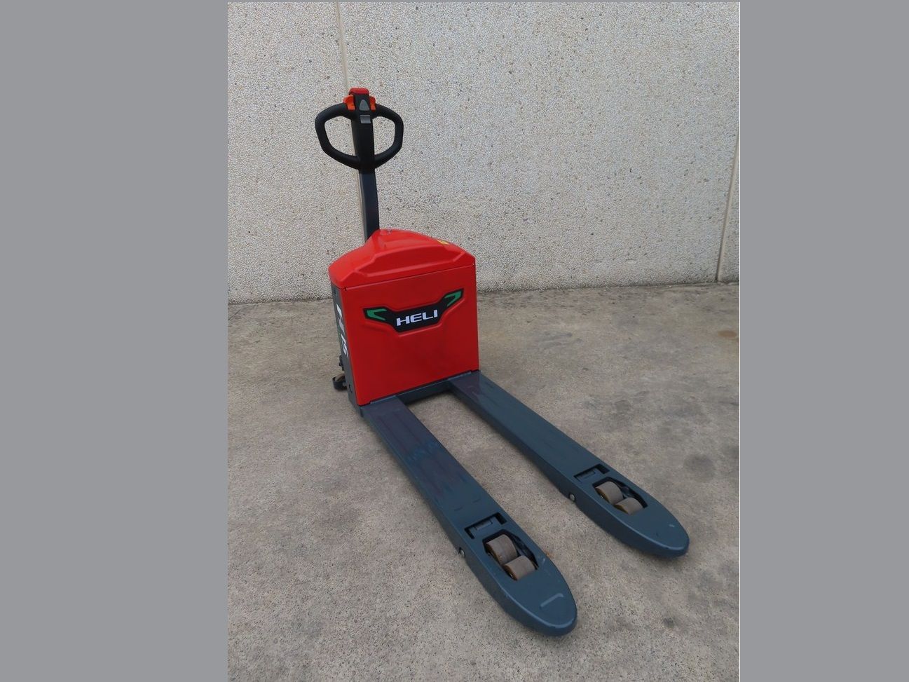 Una transpaleta roja y gris está parada en el suelo.