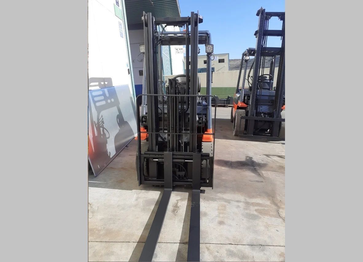 Una carretilla elevadora está estacionada en un estacionamiento con otras carretillas elevadoras