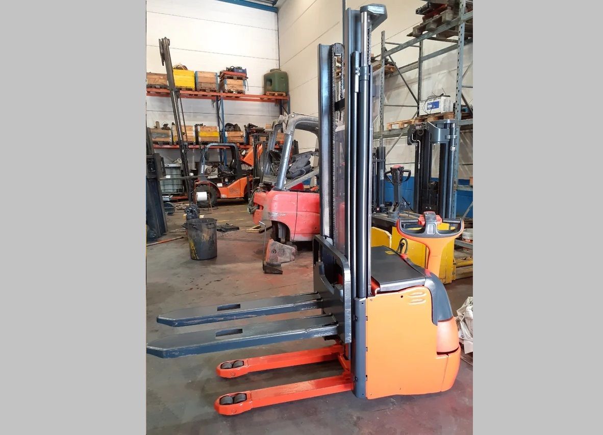 Una carretilla elevadora se encuentra en un almacén con otras carretillas elevadoras.