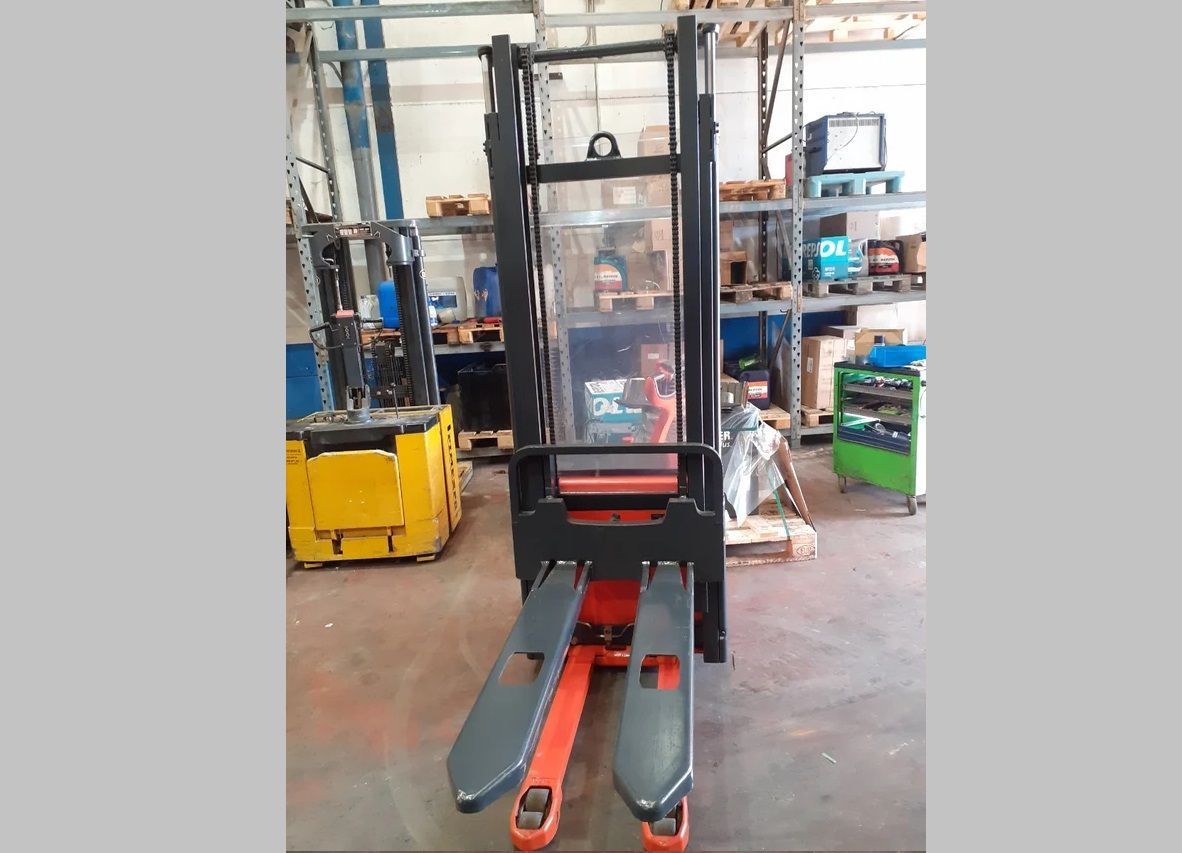 Una carretilla elevadora roja y negra está estacionada en un almacén.