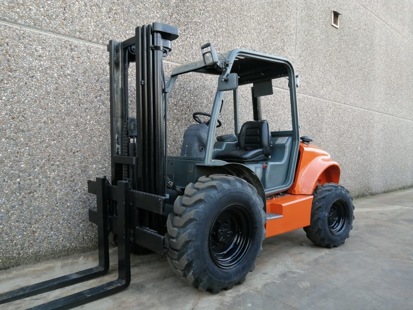 Una carretilla elevadora está estacionada delante de un muro de hormigón.