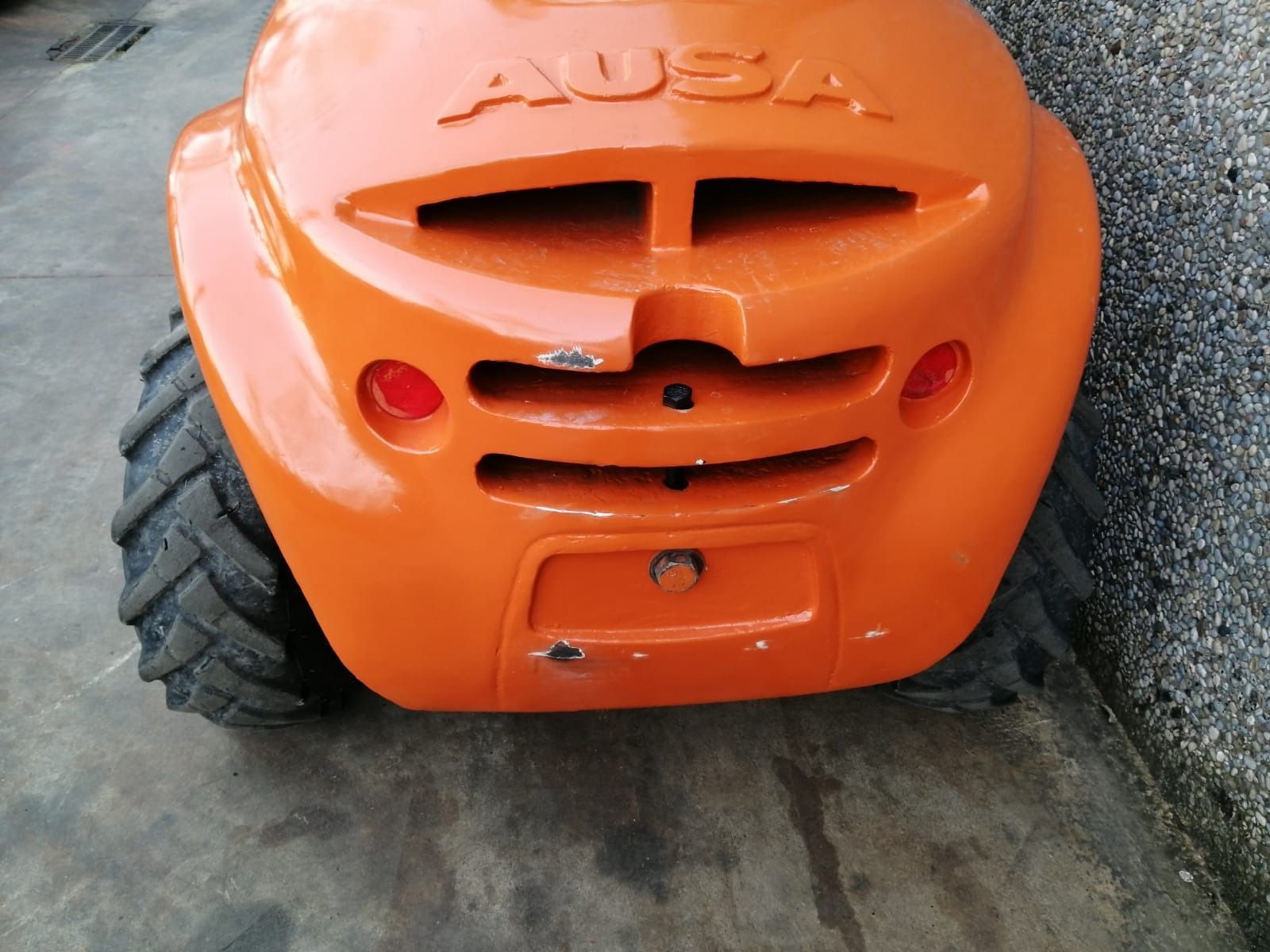 Una cortadora de césped Auba naranja está estacionada junto a una pared