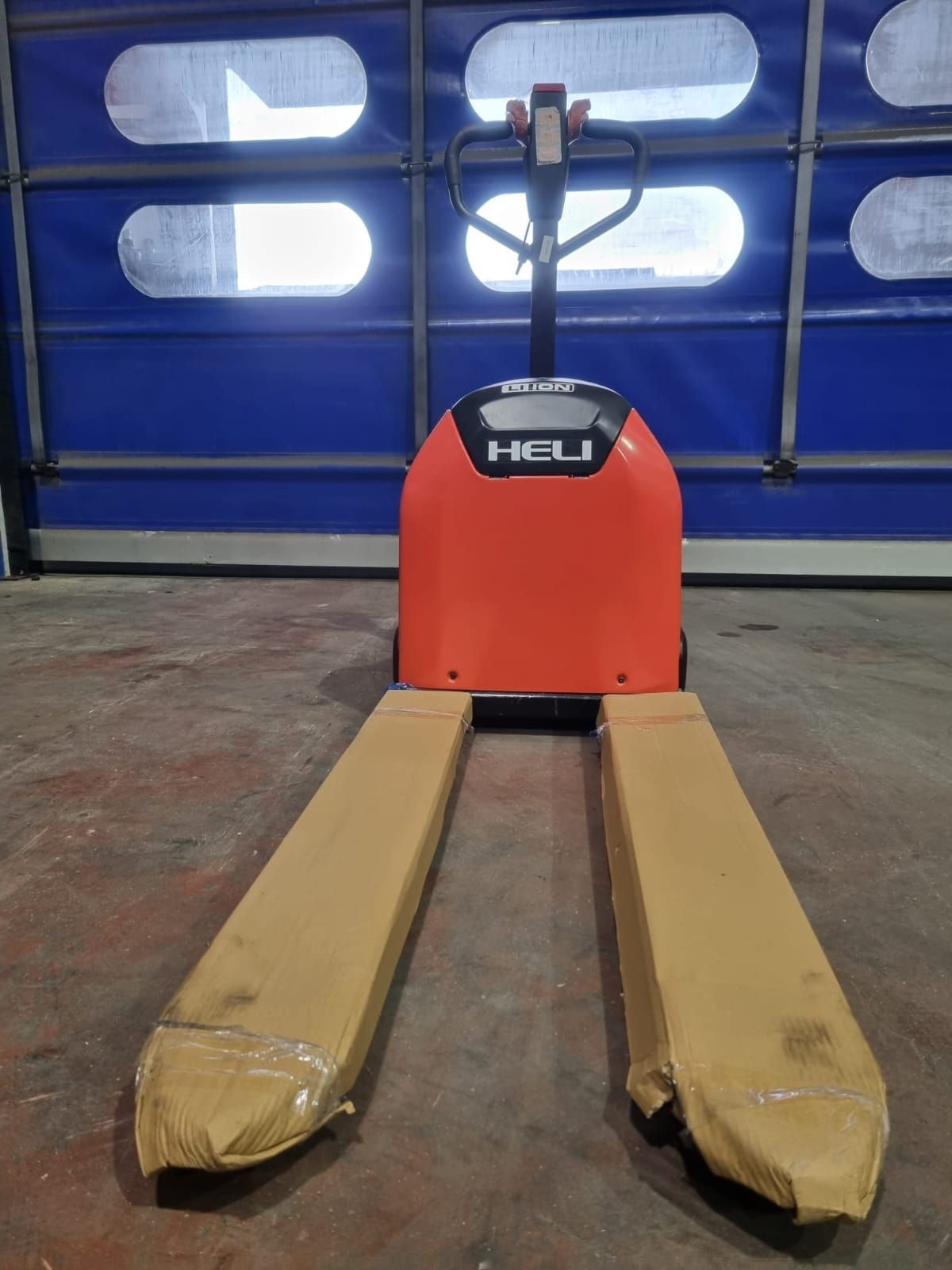 Una transpaleta roja está parada frente a una puerta de garaje azul.