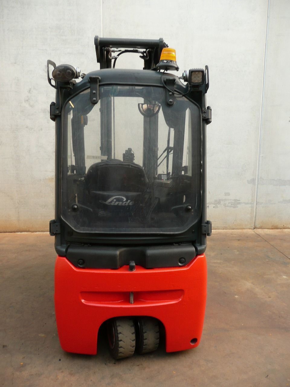 Una carretilla elevadora roja está estacionada frente a una pared blanca