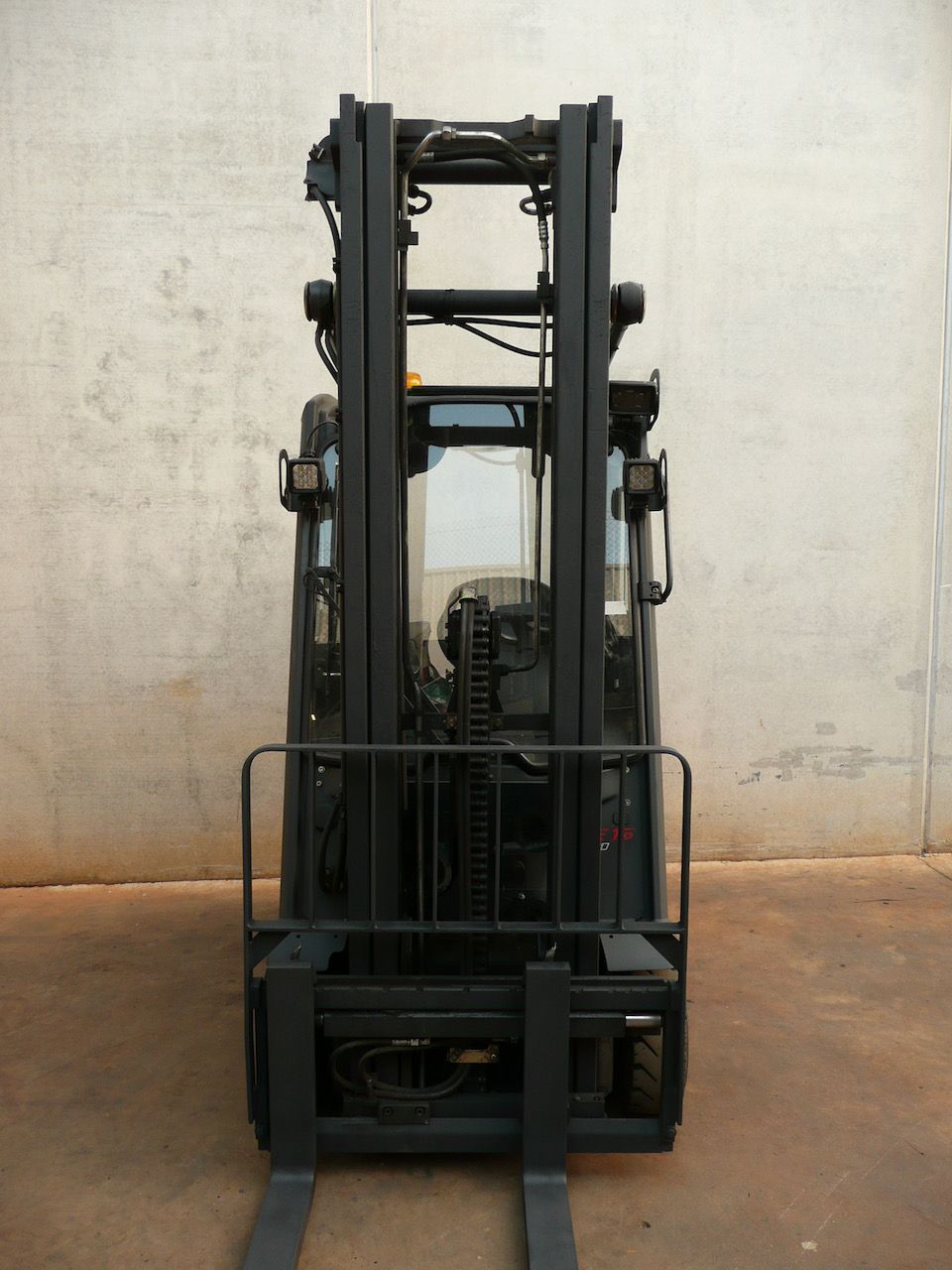 Una carretilla elevadora negra está estacionada frente a una pared