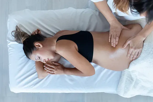 Una mujer embarazada está recibiendo un masaje en una cama.