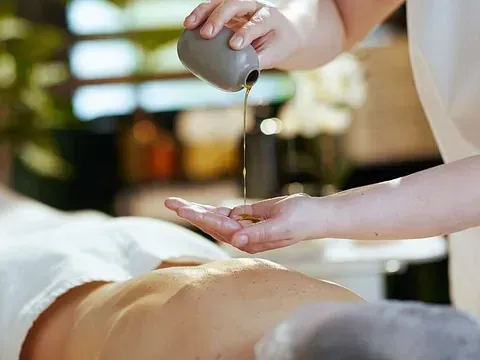 Una mujer está vertiendo aceite en la espalda de un hombre en un spa.