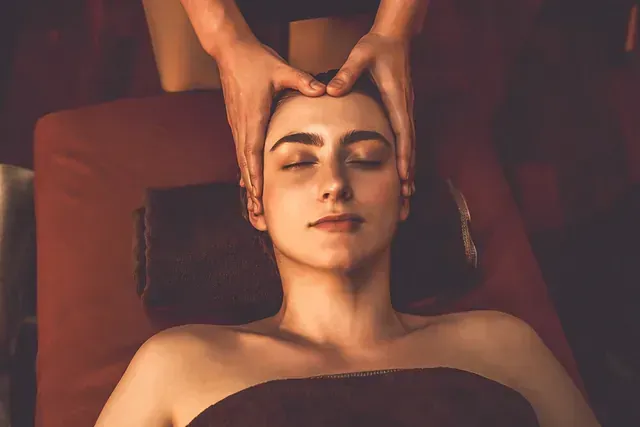 Una mujer está recibiendo un masaje de cabeza en un spa.