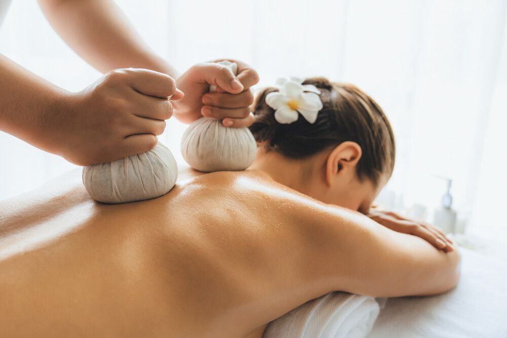 Una mujer está recibiendo un masaje en un spa con una flor en el pelo.