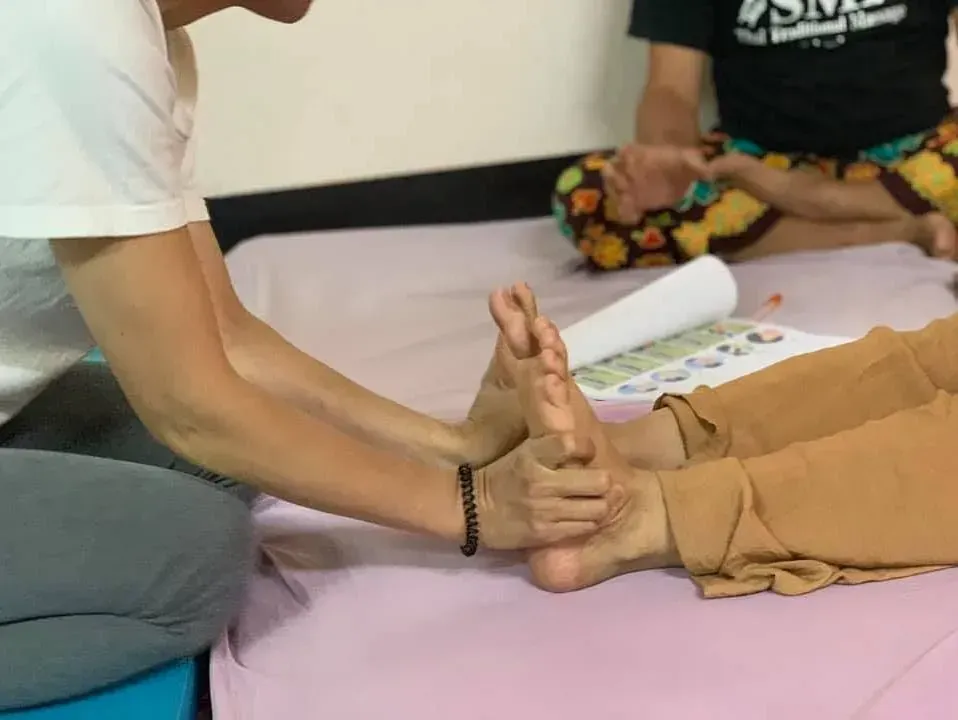 Una persona está dando un masaje de pies a otra persona en una cama.