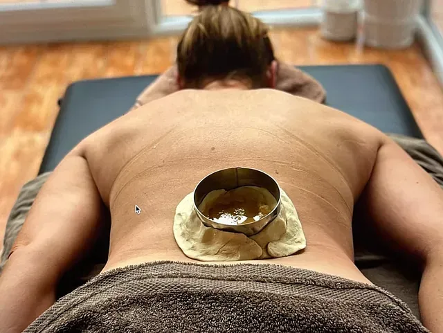 Una mujer está acostada en una cama con un cuenco en la espalda.